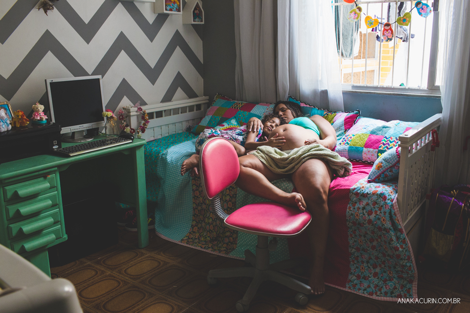 Gestante em trabalho de parto emquanrto de criança em sua casa sendo amorosamente assistida pelas duas filhas pequenas