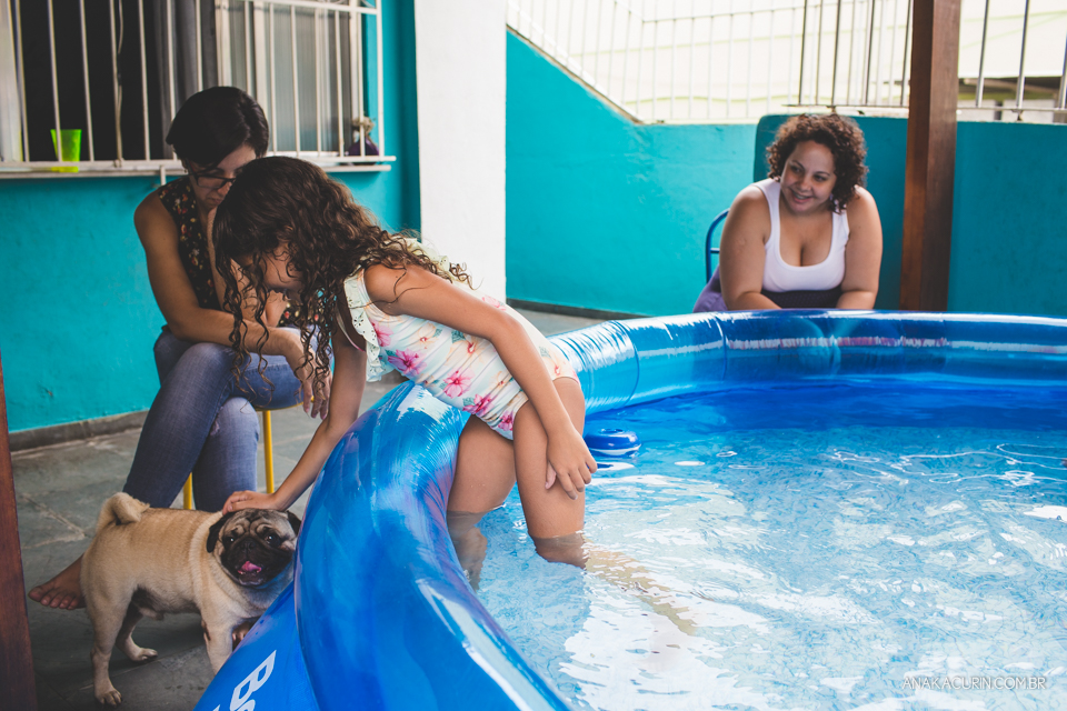 Gestante em trabalho de parto em casa, numa piscina no quintal sendo amorosamente assistida pelas duas filhas pequenas