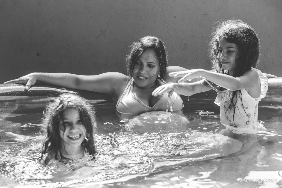 Gestante em trabalho de parto em casa, numa piscina no quintal sendo amorosamente assistida pelas duas filhas pequenas