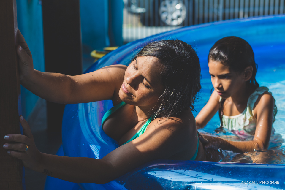 Gestante em trabalho de parto em casa, numa piscina no quintal sendo amorosamente massageada por uma de suas filhas