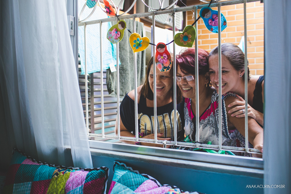 Família de gestante espiando pela janela de casa o trabalho de parto com expressões de felicidade e ansiedade.