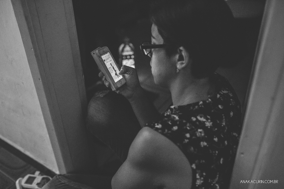 Parteira olhando o celular sentada no chão