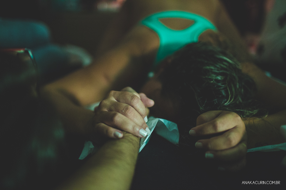 Festante em trabalho de parto no quarto de casa sendo assistida pelo marido e doula