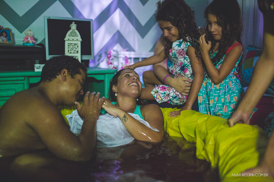 Filha afaga a cabeça da mãe recém parida na piscina de casa