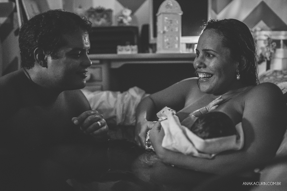 esposa e marido se olham felizes com a chegada do bebê em seu colo