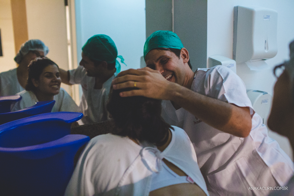 Parto natural hospitalar de Sofia, que aconteceu na Perinatal de Laranjeiras e teve a fotografia feita por Ana Kacurin. Pai sorri e faz carinho na mãe.