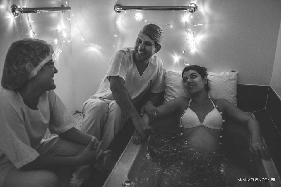 Parto natural hospitalar de Sofia, que aconteceu na Perinatal de Laranjeiras e teve a fotografia feita por Ana Kacurin. Pai, doula e gestante sorrindo.