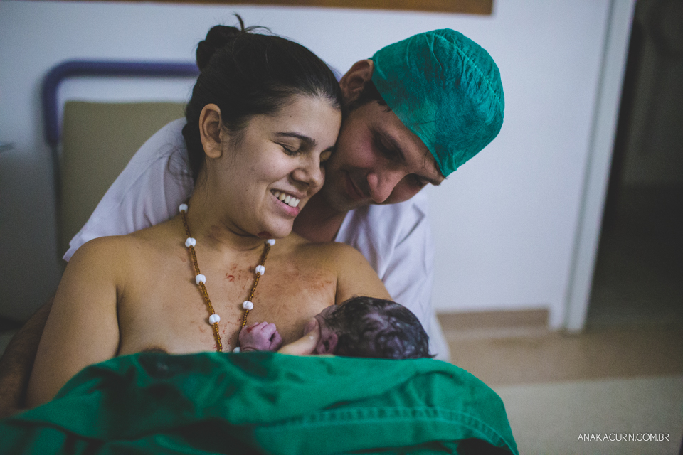 Parto natural hospitalar de Sofia, que aconteceu na Perinatal de Laranjeiras e teve a fotografia feita por Ana Kacurin. Mãe recém parida sorri com bebê no colo.