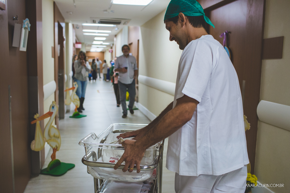 Parto natural hospitalar de Sofia, que aconteceu na Perinatal de Laranjeiras e teve a fotografia feita por Ana Kacurin. Pai leva filha recém nascida pelo corredor do hospital.