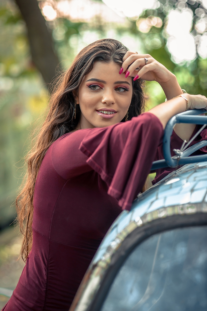 Retrato da linda modelo de olhos verdes usando um vestido vermelho encostada em um fusca durante seu ensaio fotográfico. Foto por Marco Moscarelli Fotógrafo.