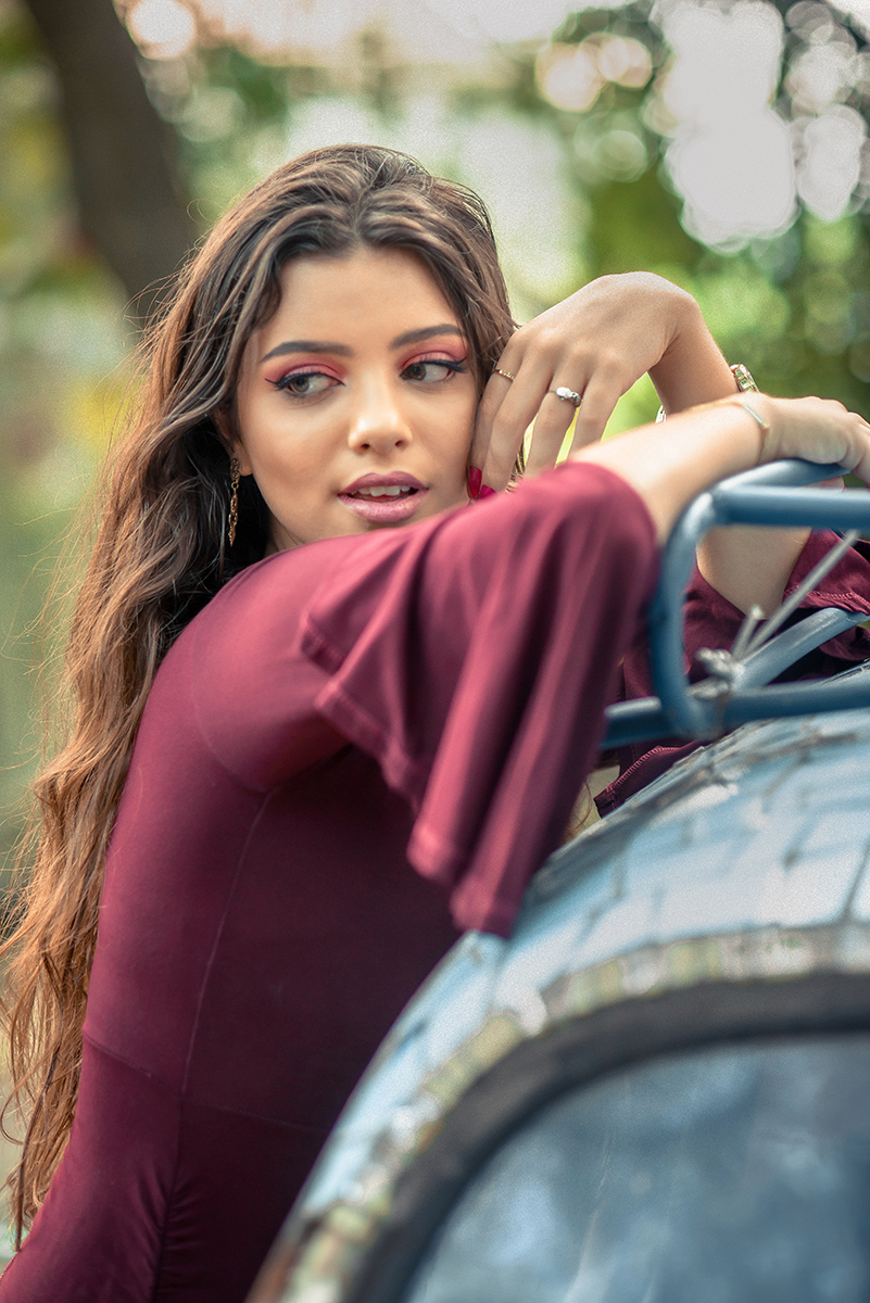 Retrato da linda modelo de olhos verdes usando um vestido vermelho encostada em um fusca durante seu ensaio fotográfico. Foto por Marco Moscarelli Fotógrafo.