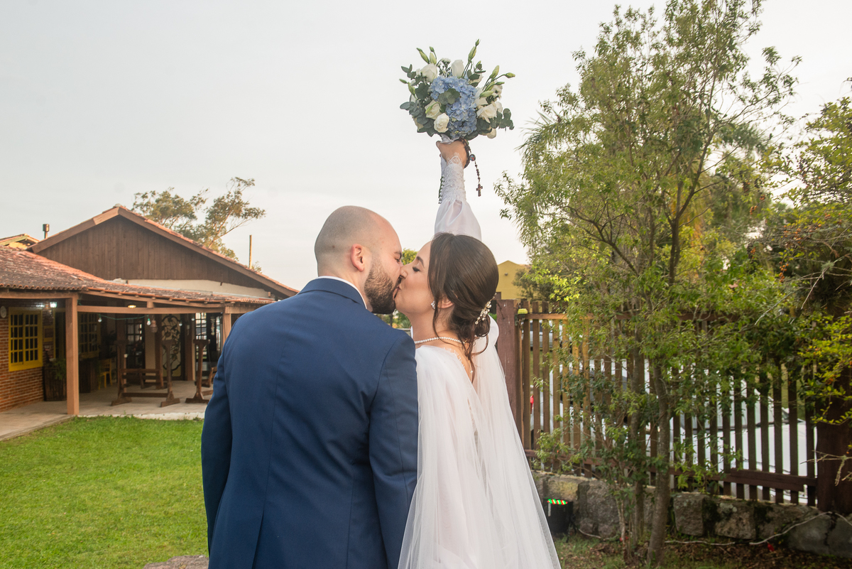 Saída dos noivos após o casamento. Noiva erguendo o buquê. Fotografia em contra luz do casal de noivos durante a cerimônia de casamento ao ar livre. Foto por Marco Marco Moscarelli Fotógrafo