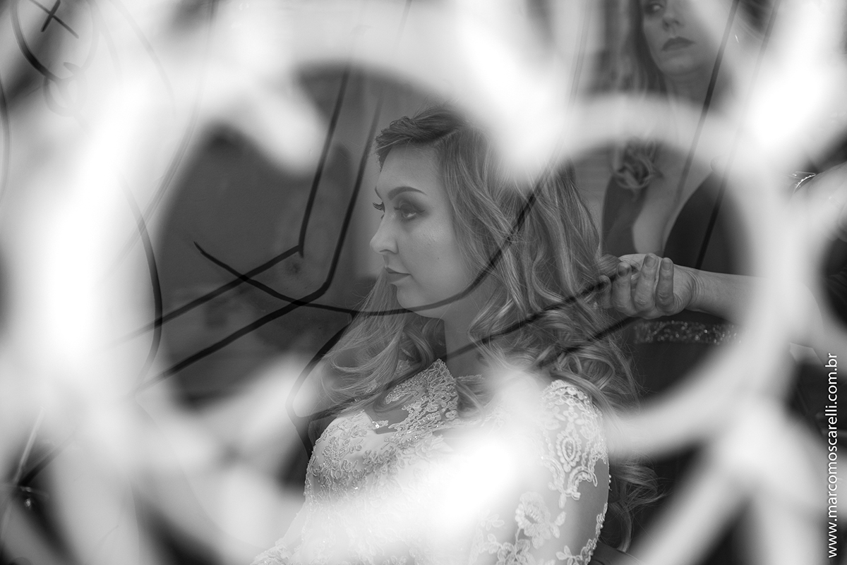 Foto em Preto e Branco da noiva atravas do vidro em quanto faz a maquiagem no Making of da noiva. Foto-Marco Moscarelli