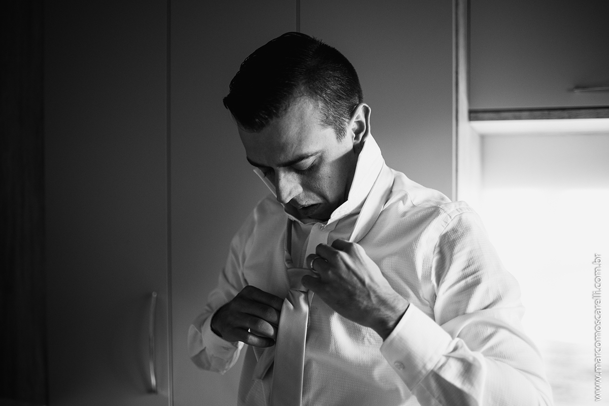 Foto em preto e branco do noivo arrumando a gravata durante Making of antes do casamento. Foto- Marco Moscarelli