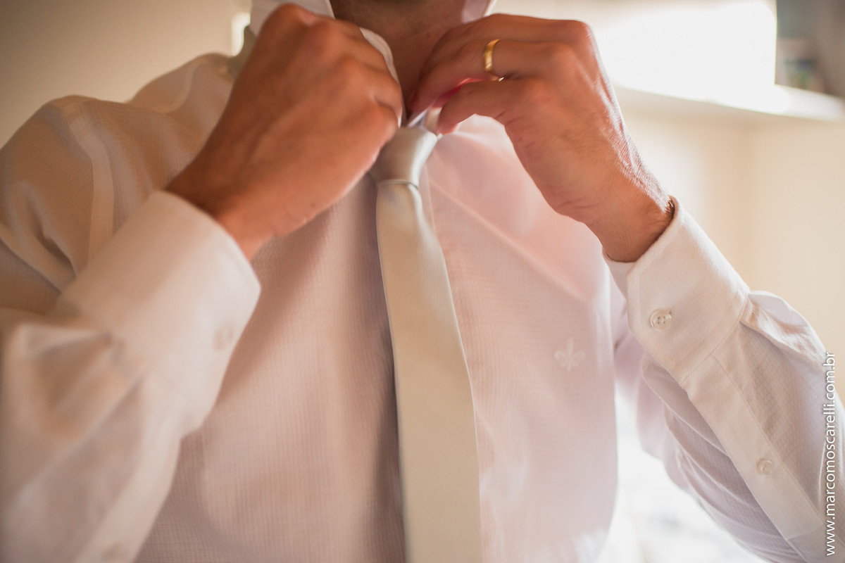 Detalhe das mãos do noivo arrumando colarinha da camisa durnte seu Making of antes do casamento. Foto por Marco Moscarelli