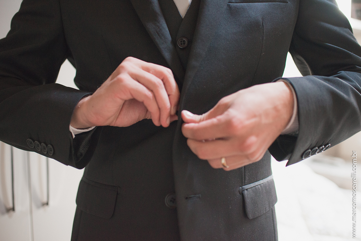 Foto do detalhe do noivo abotoando o colete durante Making of antes do casamento. Foto por Marco Moscarelli