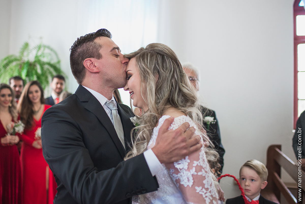 Noivo beijando a testa da noiva durante o casamento. Foto por Marco Moscarelli