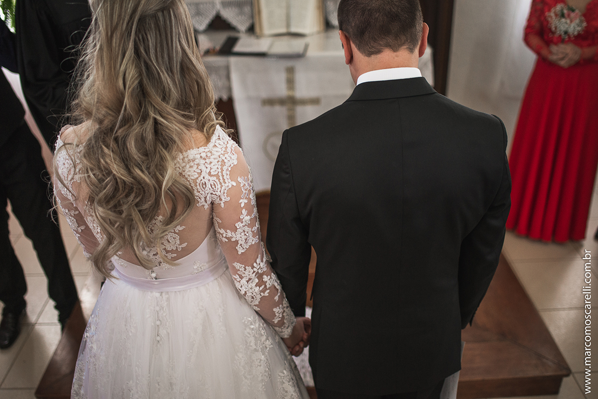 Foto dos noivos ajoelhados no altar durtante o casamento. Foto por Marco Moscarelli