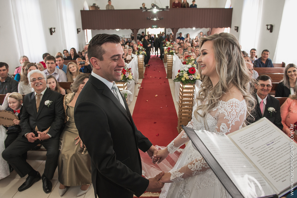Noivos de mãos dadas no altar da igreja durante o casamento. Foto por Marco Moscarelli