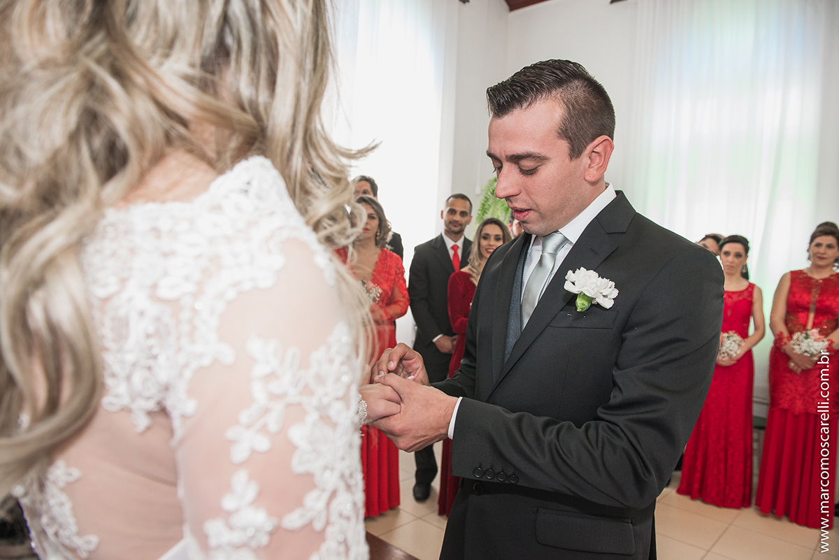 Noivo colocando a alinça no dedo da noiva durante o casamento. Foto por Marco Moscarelli