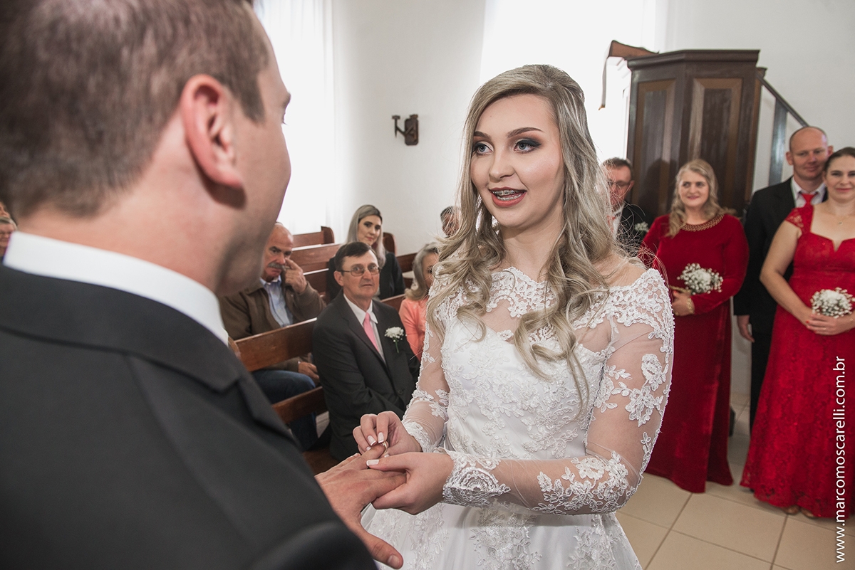 Noiva colocando a aliança no dedo do noivo durante o casamento. Foto por Marco Moscarelli