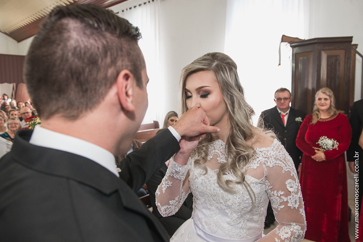 Noiva beijando a mão do noivo logo após colocar a alinaça durante o casamento. Foto por Marco Moscarelli