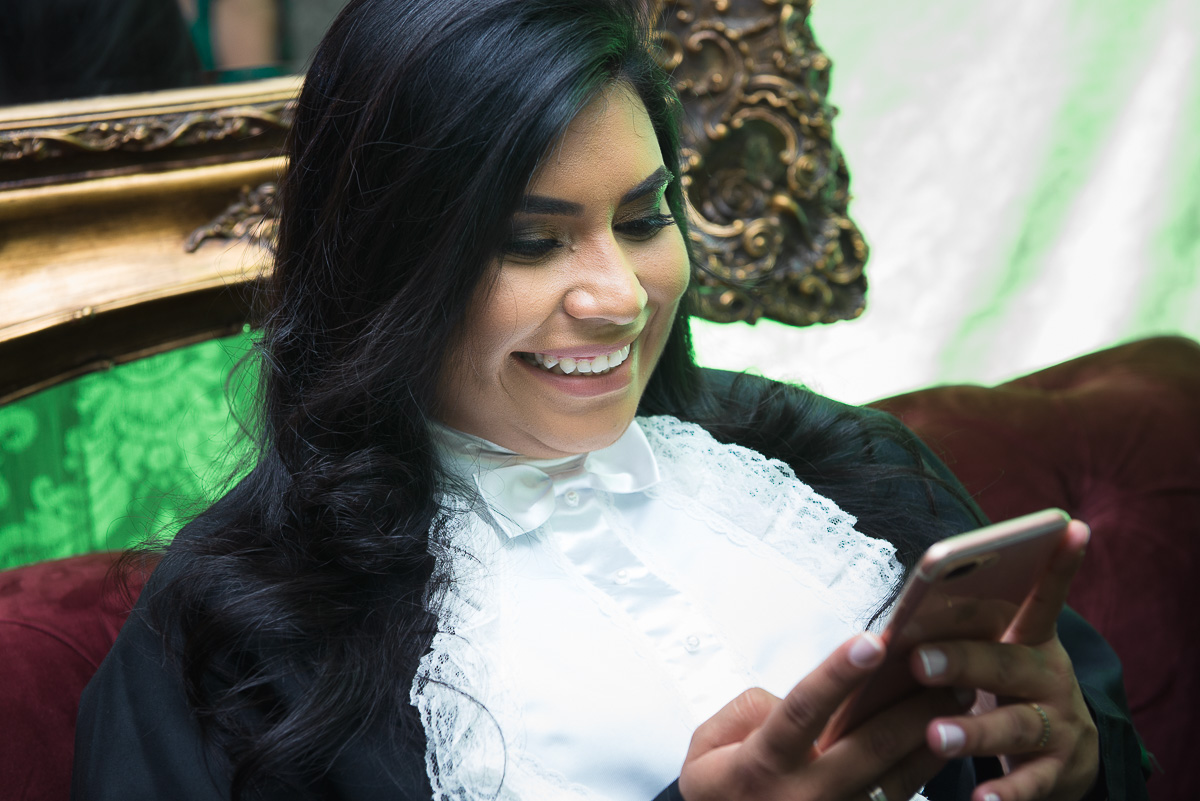 Formanda do curso de medicina sorrindo unsado o celular. Foto - Marco Moscarelli