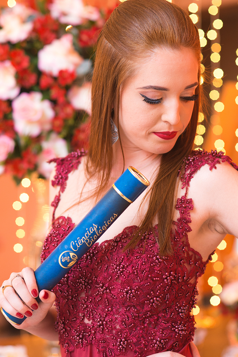 Formanda posando para retrato com seu canudo de formatura em sua recepção de formatura. Marco Moscarelli.