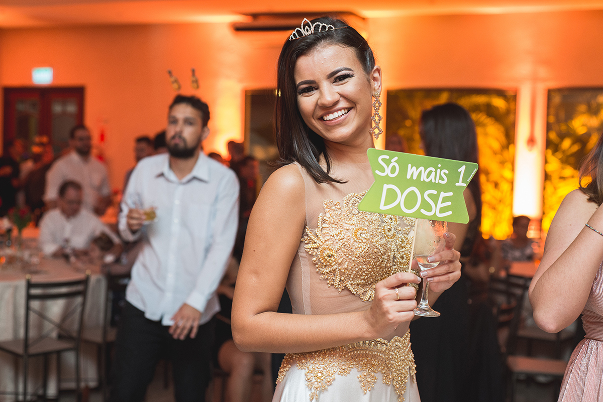 Fotografia da formanda dando um belo sorriso com uma plaquinha divertida escrito gratidão. Foto por Marco Moscarelli.