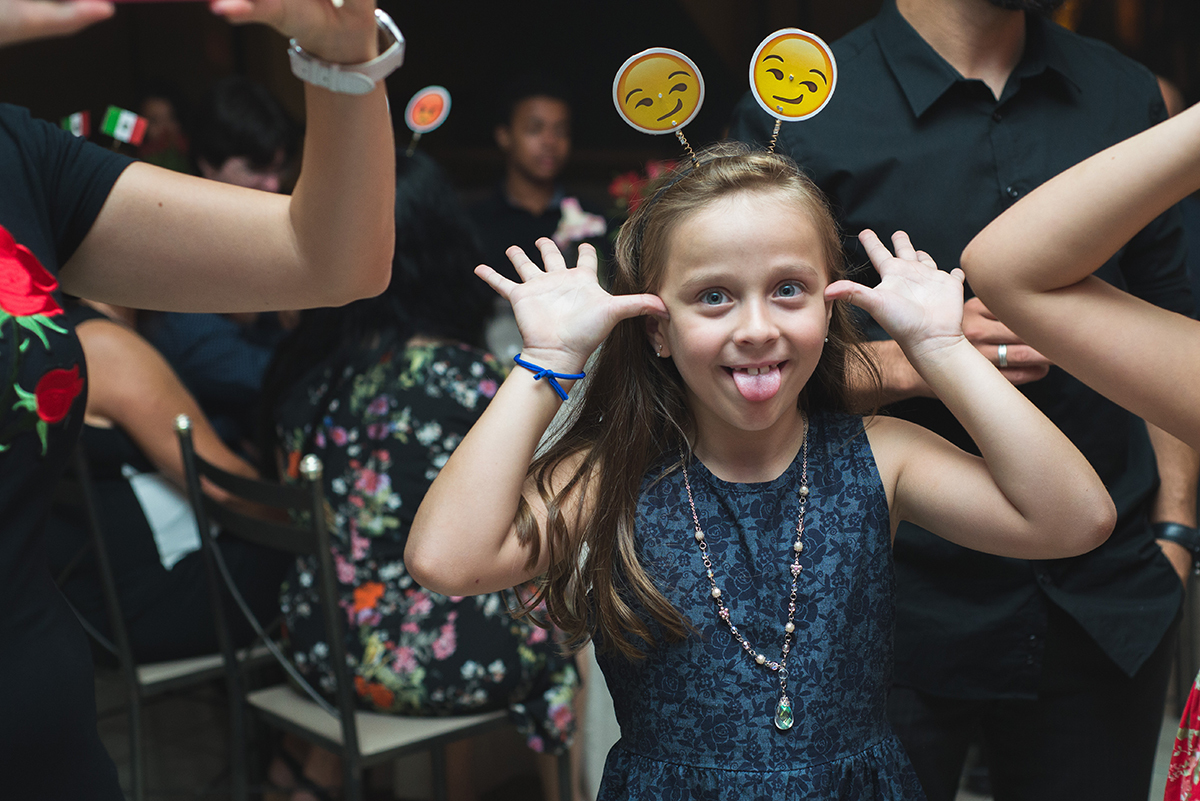 Fotografia de uma convidada criança fazendo careta para o fotografo durante  a recepção de formatura. Foto por Marco Moscarelli