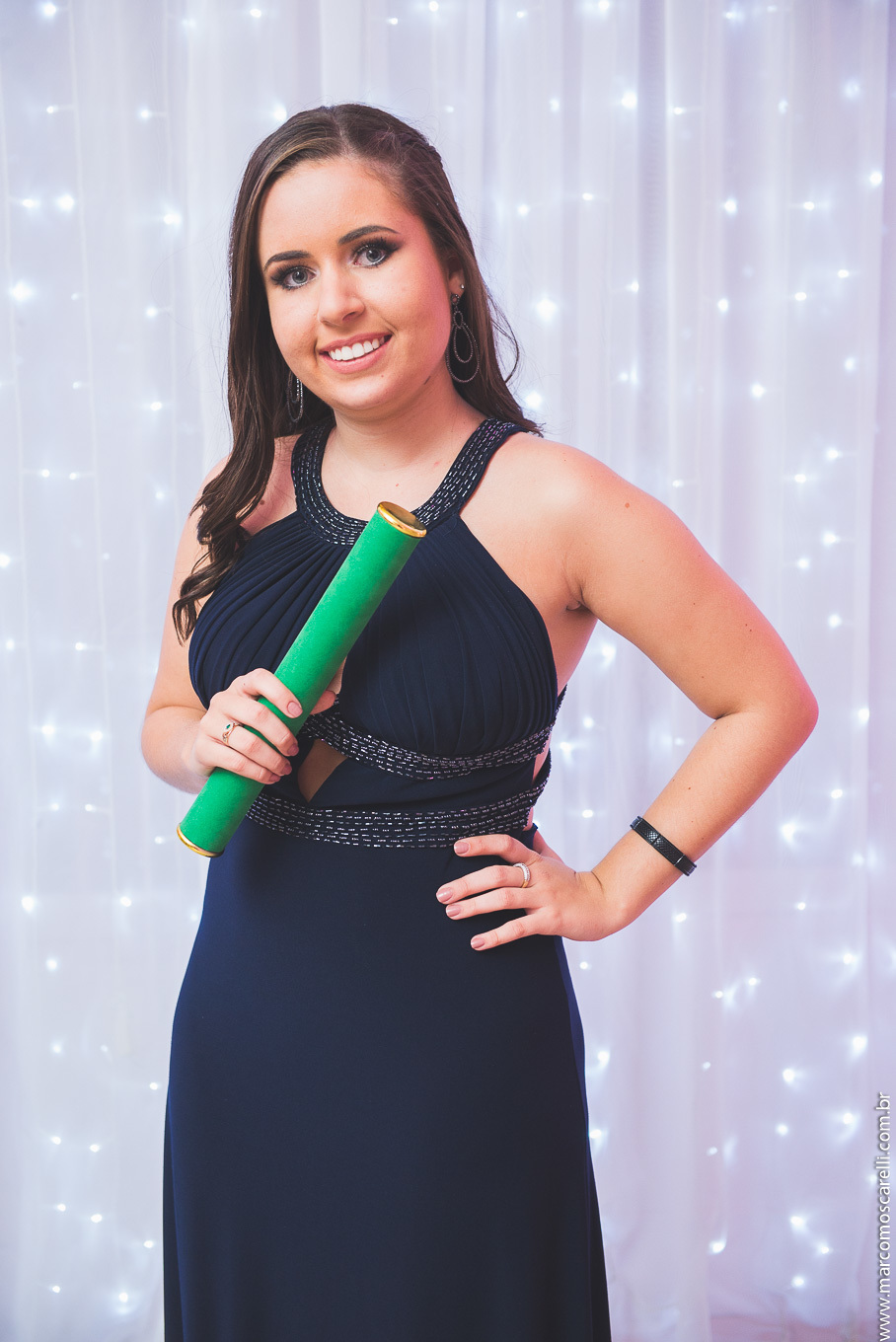 Retrato da formanda posando para a foto segurando seu canudo de formatura.