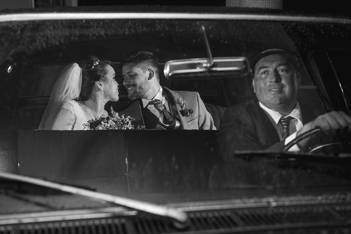 Fotografia dos noivos em preto e branco dentro do carro dos noivos após a cerimônia de casamento. Foto por Marco Moscarelli Fotografo.