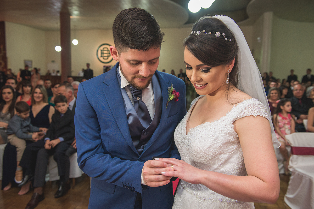 Noivo colocando aliança de casamento no dedo da noiva. Foto por Marco Moscarelli Fotografo