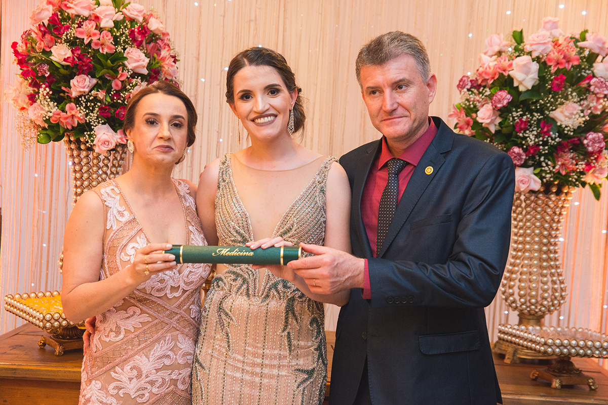 Formanda de medicina posando para foto junto aos seus pais. Foto por Marco Moscarelli