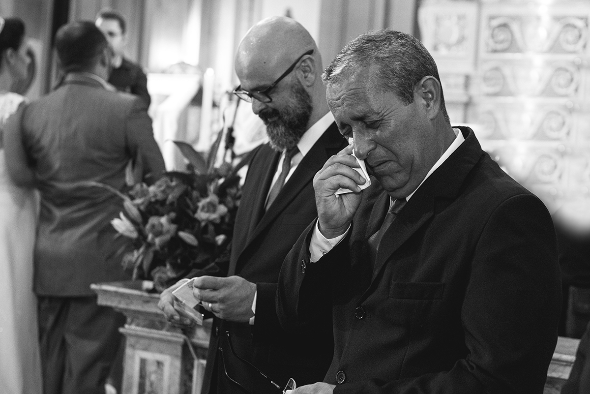 Lindo momento do padrinho emocionado com os noivos ao fundo. Foto por Marco Moscarelli