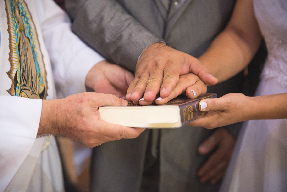 Lindo momento dos noivos com as mãos na bíblia durante a cerimônia de casamento. Foto por Marco Moscarelli