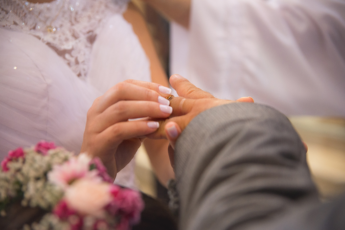 Momento especial em que a noiva coloca a aliança no dedo do noivo durante a cerimônia de casamento. 
