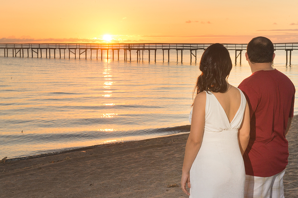 Noivos admirando o nascer do sol na praia do laranjal durante seu ensaio pré-wedding. Foto por Marco Moscarelli