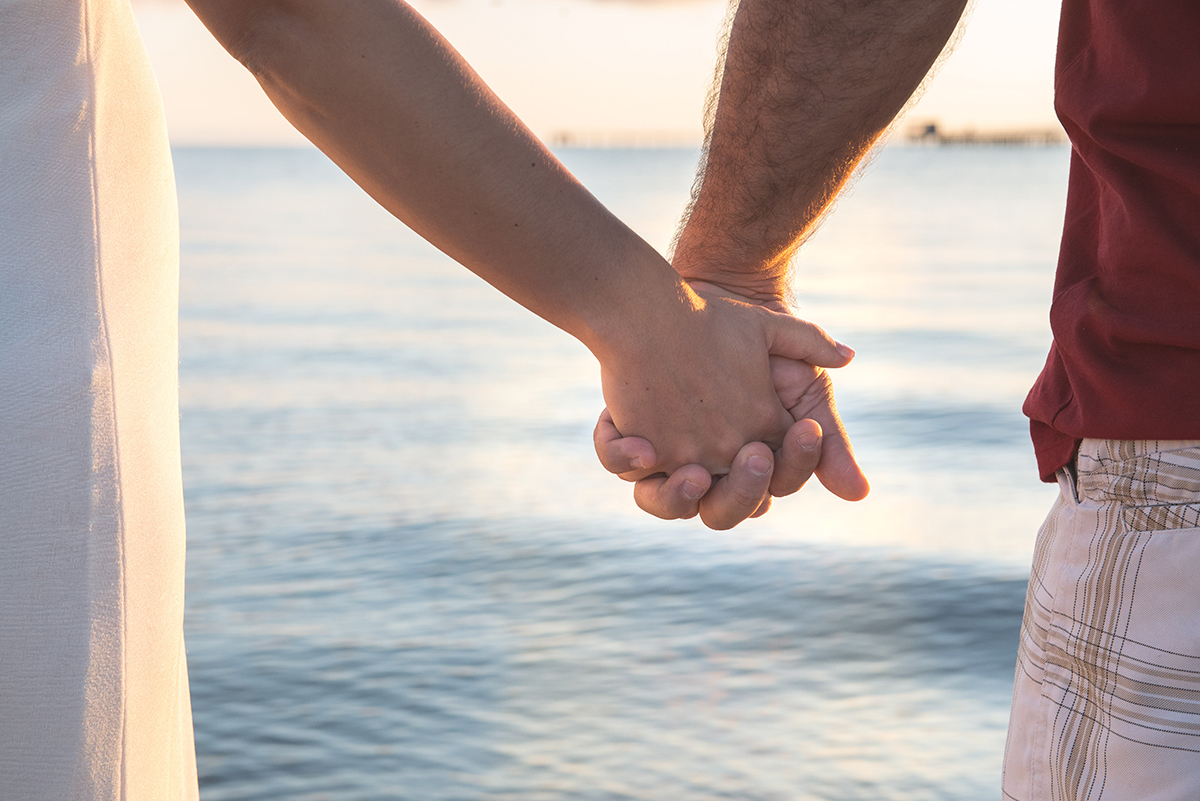 Noivos de maos dadas caminhando na praia duirante o ensaio de casal pré-wedding. Foto por marco Moscarelli