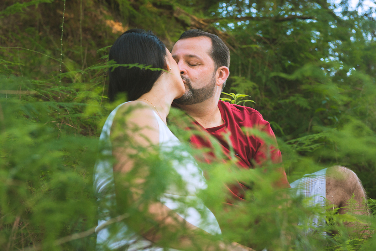 Noivo beija a noiva  em meio a vegetação durante as fotos do seu ensaio de casal pré-wedding. Foto 