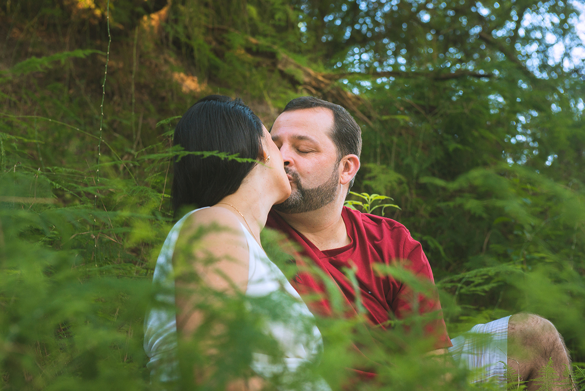 Noivo beija a noiva  em meio a vegetação durante as fotos do seu ensaio de casal pré-wedding. Foto 