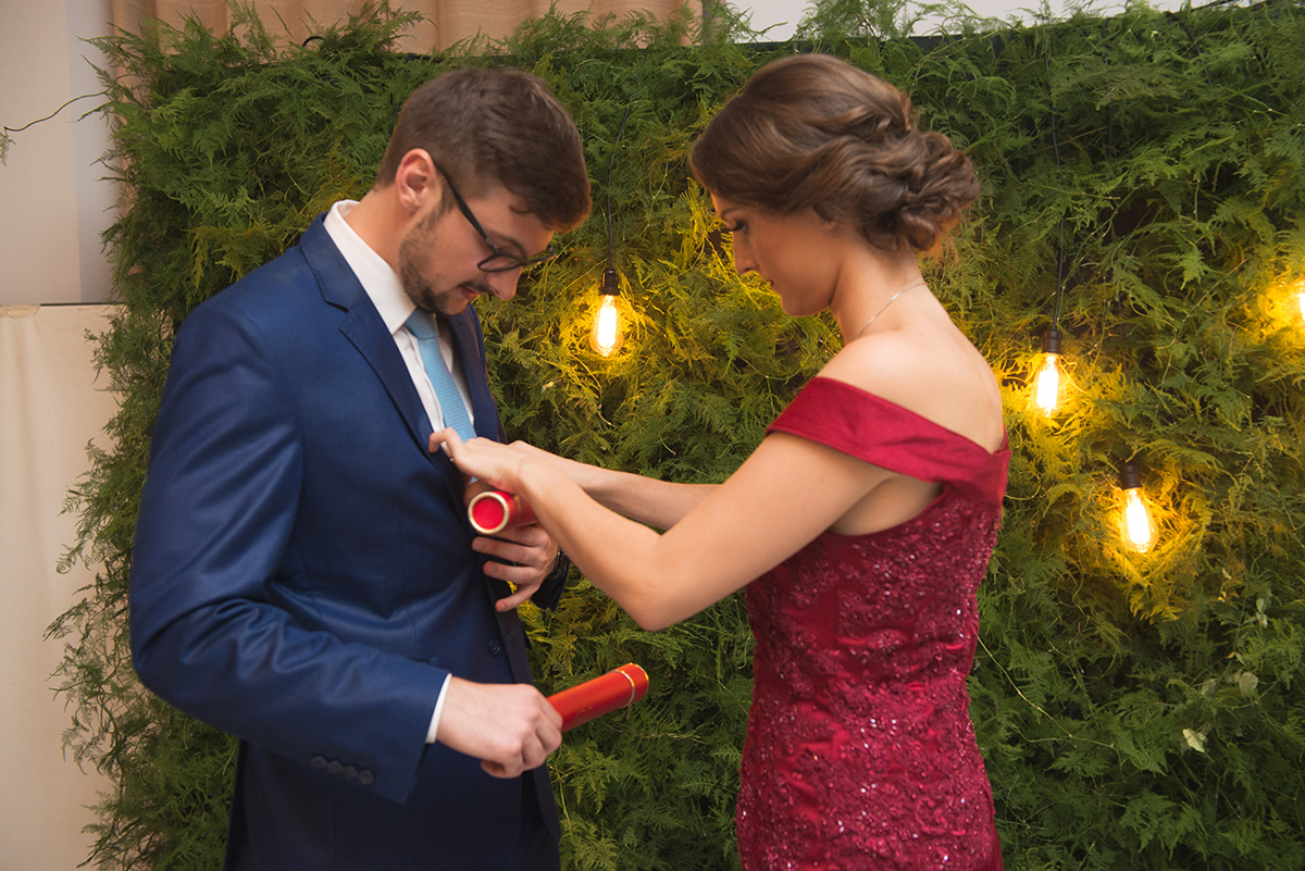 Noiva arrumando o noivo formando antes da seção de fotos na recepção de formatura. Foto por Marco Moscarelli.