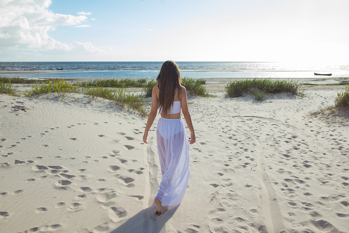 Linda foto da debutante caminhando pela praia durante seu ensaio de 15 anos na praia da capilha. Foto por Marco Moscarelli Fotografo.