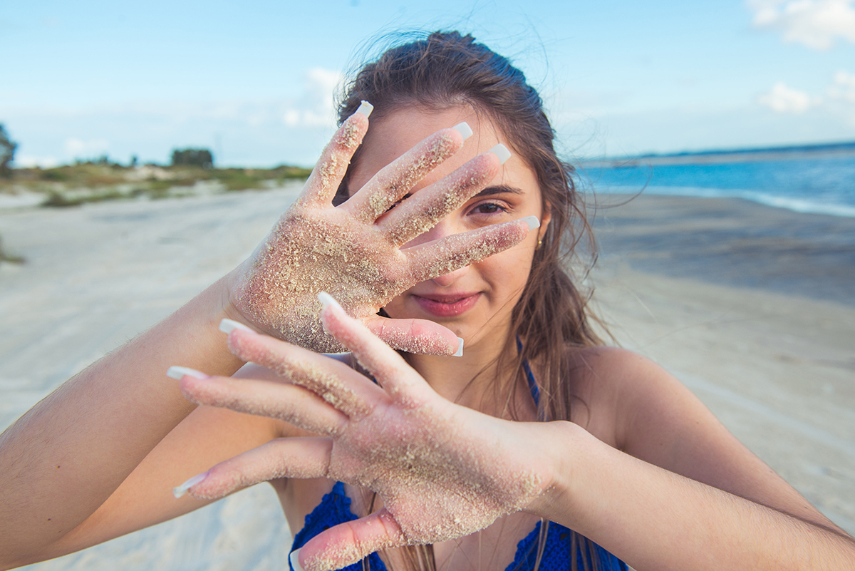 Debutante em uma foto descontraída com a mão suja de areia durante seu ensaio fotográfico na praia da capilha. Foto por Marco Moscarelli