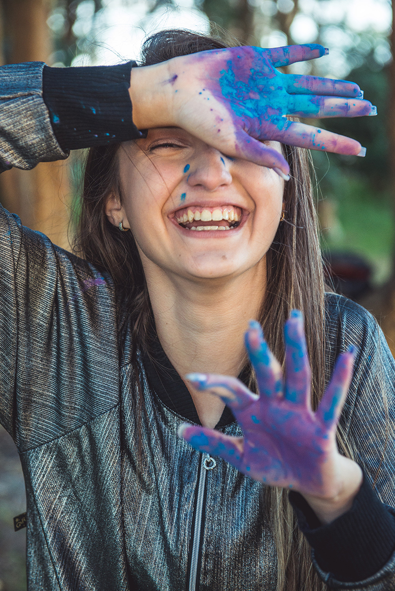 Debutante em uma foto descontraída com a mão suja de tinta durante seu ensaio fotográfico na praia da capilha. Foto por Marco 