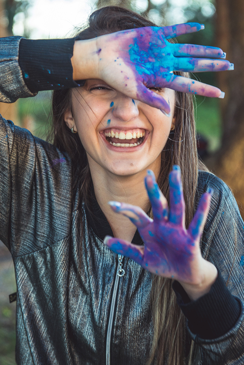Debutante em uma foto descontraída com a mão suja de tinta durante seu ensaio fotográfico na praia da capilha. Foto por Marco 