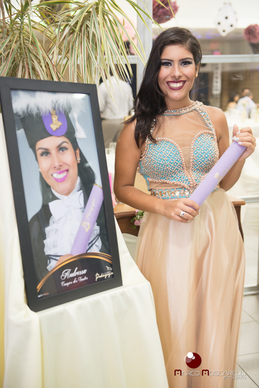 Formanda posando ao lado do seu quadro de formatura