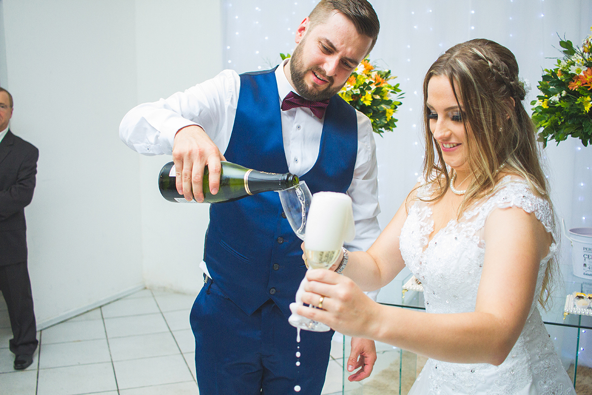 Noivo servindo o espumante até derramar na taça da noiva durante a recepção dos noivos. Foto por Marco Moscarelli Fotografo.