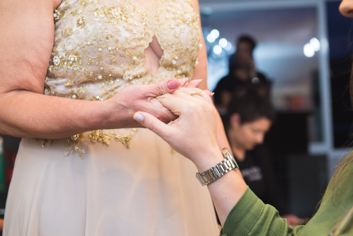 Momento de carinho entre a noiva e sua mãe segurando as mãos durante o make da noiva momentos antes do casamento. 