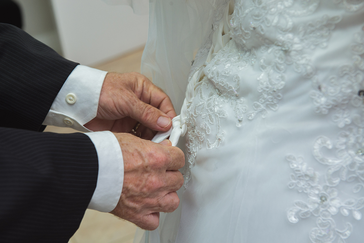 Pai da noiva ajustando o vestido da filha momentos antes de ir para a igreja para a cerimônia de casamento. Foto por Marco Moscarelli Foptografo